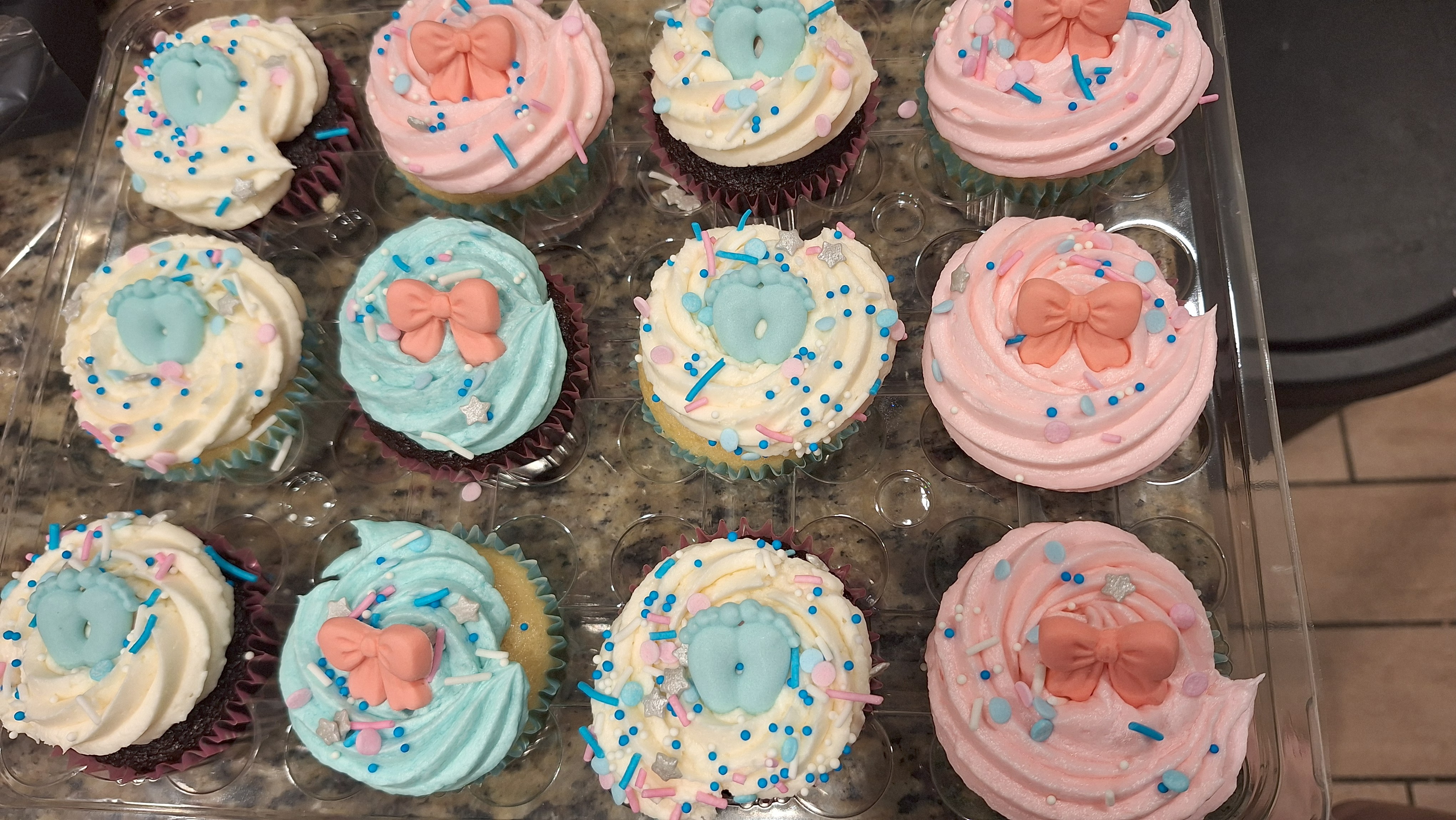 Pastel cupcakes with bows and baby-themed toppers